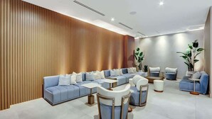 A modern lounge area with a sectional sofa, armchairs, and small tables. - Modern Studio w/ Balcony Near Brickell & Downtown (Miami)