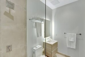 Une salle de bain moderne équipée d’une douche, de toilettes, d’un lavabo et d’un porte-serviettes.
