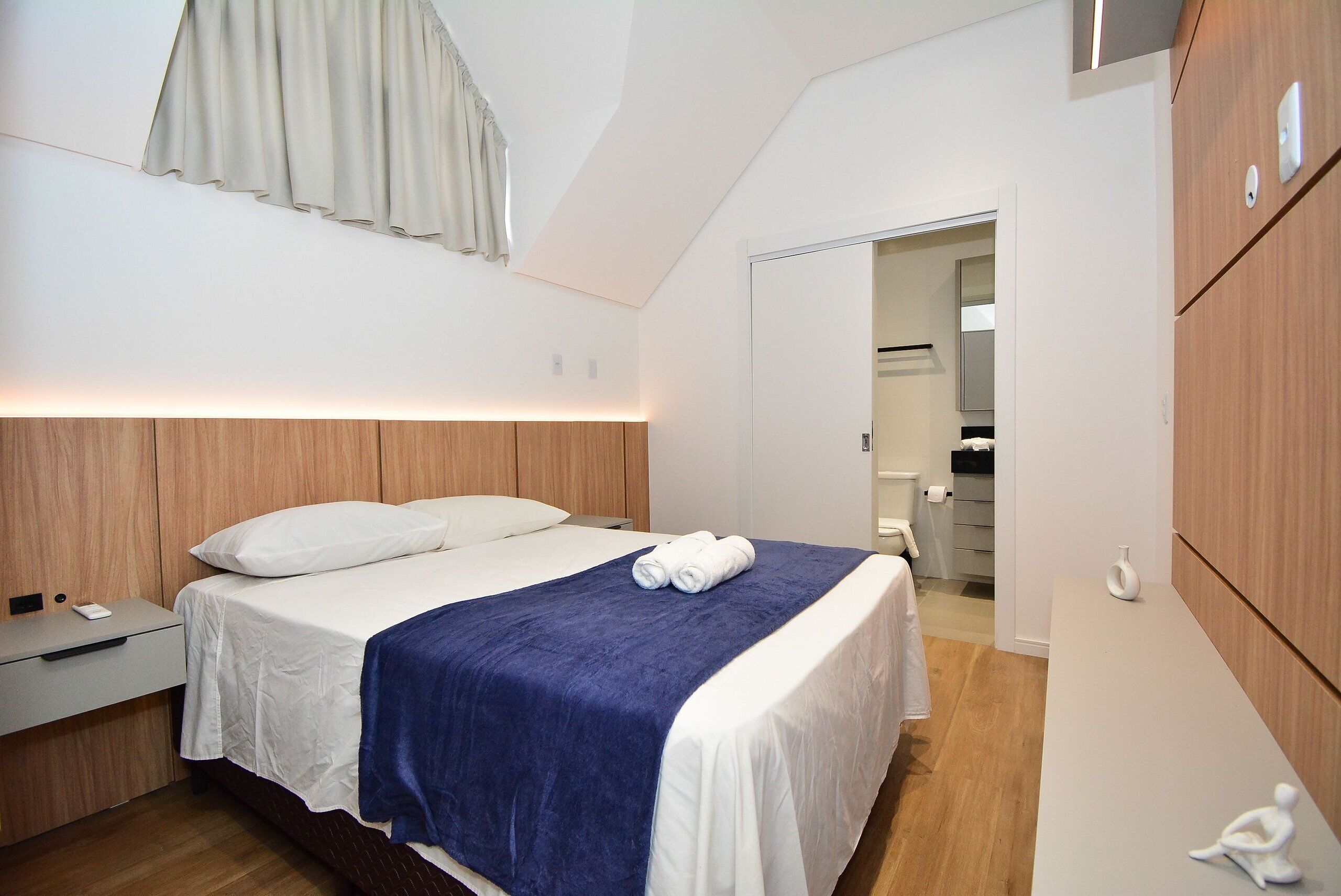 A hotel room with a bed, bedside table, and a wardrobe.