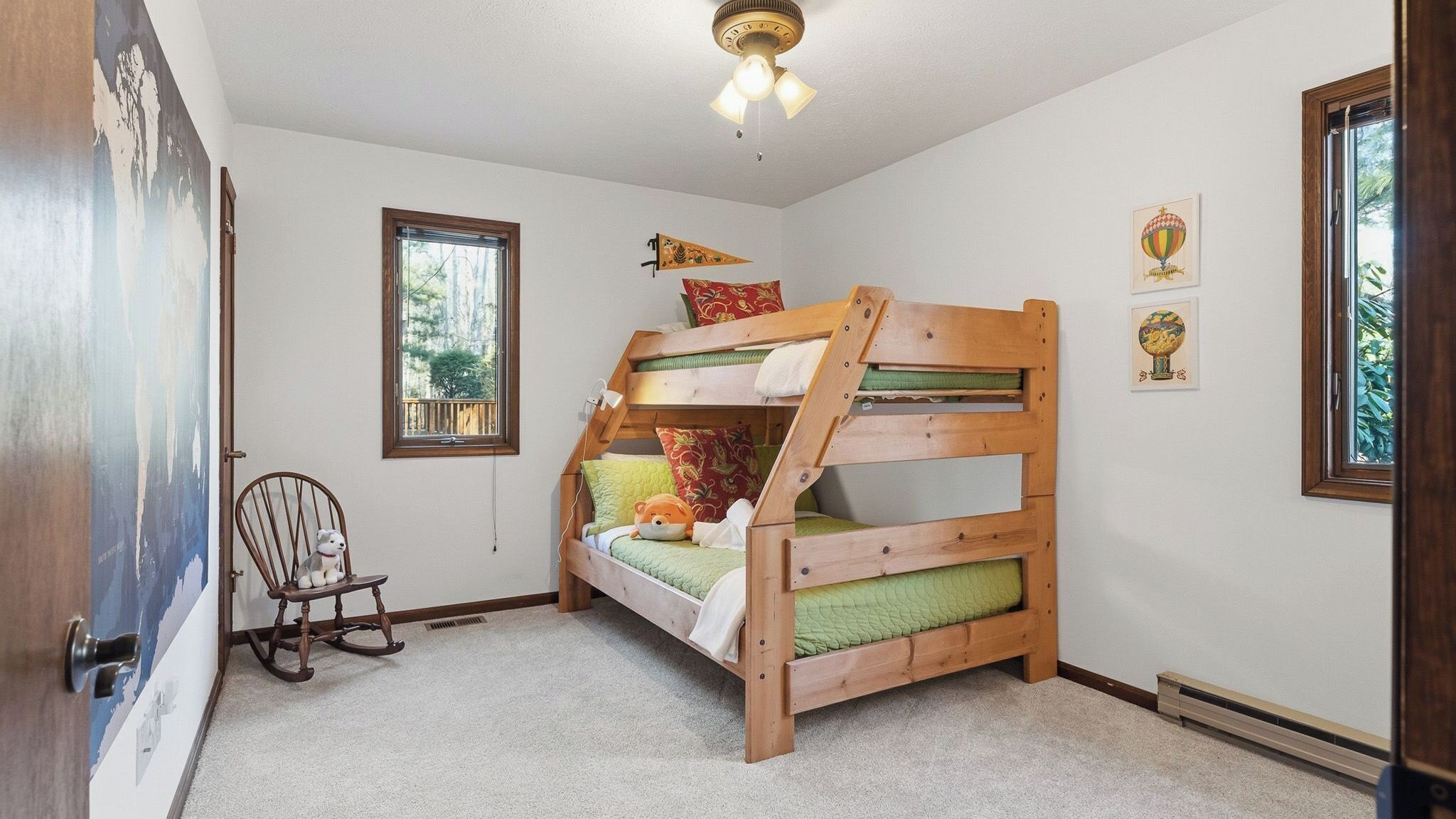 A bunk bed room with a rocking chair, a window, and a ceiling fan.
