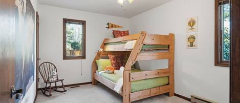 A bunk bed room with a rocking chair, a window, and a ceiling fan.