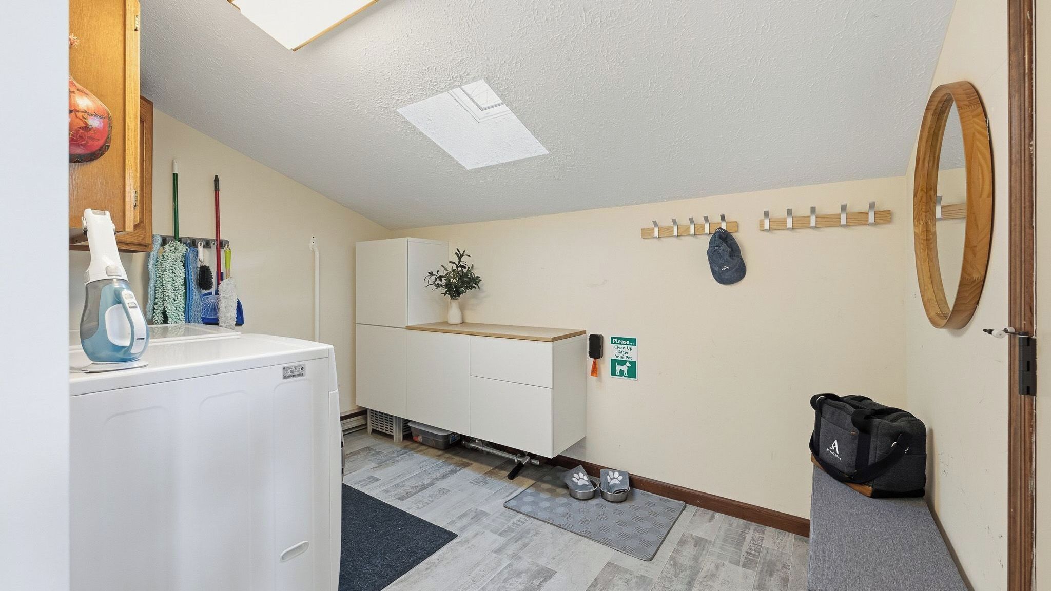 Une petite pièce propre, équipée d’un lave-linge, d’un miroir, d’un porte-manteau, d’un espace pour les déchets des animaux de compagnie et d’un meuble à chaussures.