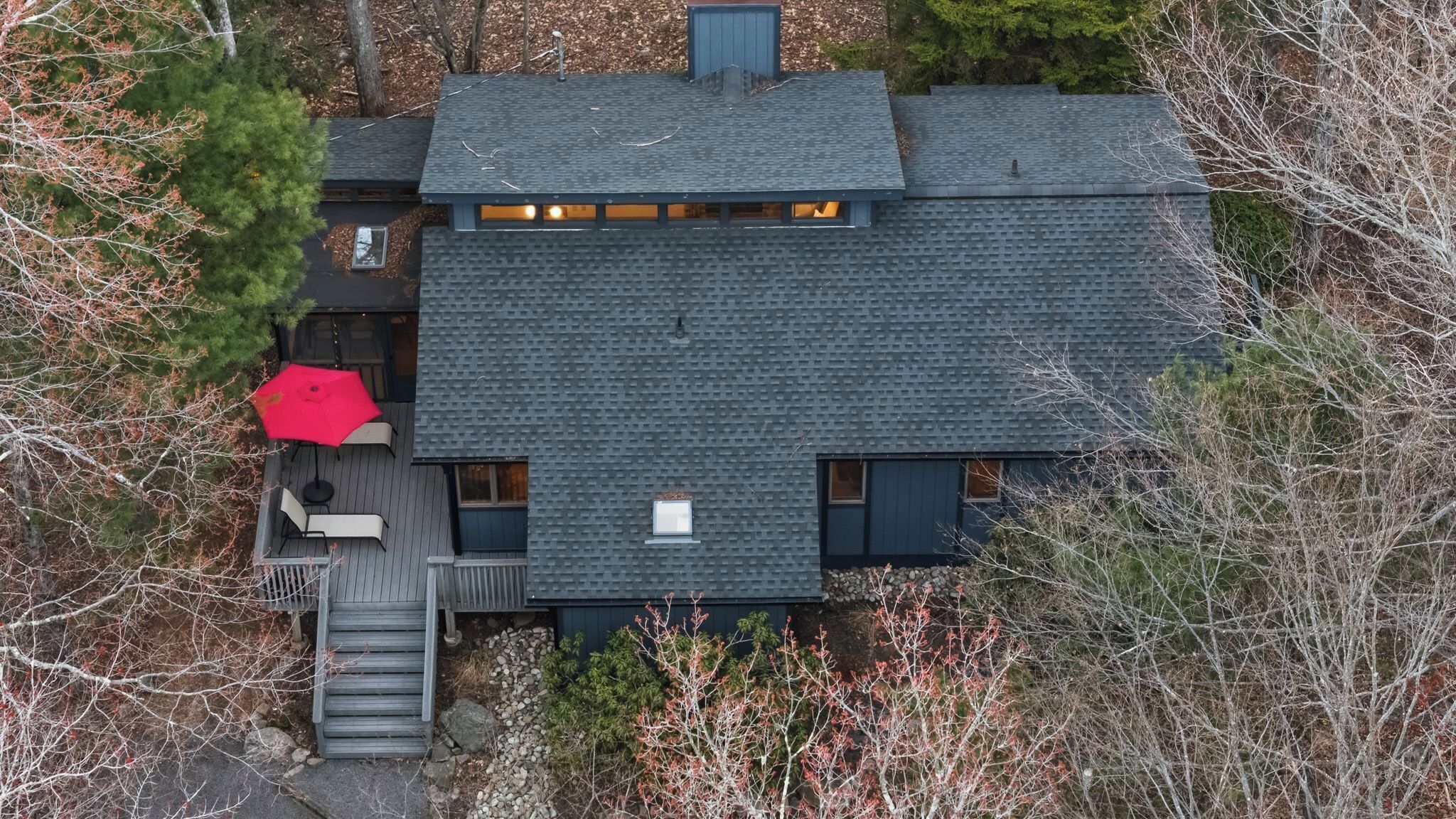 A modern house with a sloped roof, a deck, and a red umbrella.