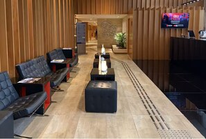 A hotel lobby with a reception desk, seating area, and a television screen. - Meliá Flat Block B 307 (Brasília)