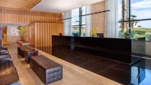 Eine moderne Lobby mit Empfangsschalter, Sitzgelegenheiten und großen Fenstern.