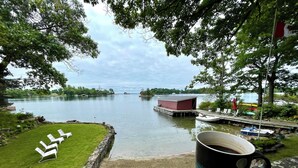 Näkymä järvelle, jossa on laituri, aurinkotuoleja ja punainen rakennus.