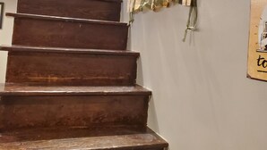 Eine Holztreppe führt zu einer Tür mit einem kleinen Fenster.