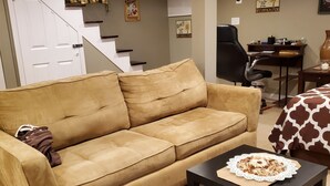 Ein Wohnzimmer mit Sofa, Couchtisch mit Dekoration, Treppe und Schreibtisch mit Stuhl.