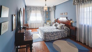 A bedroom with a bed, a desk, a chair, a lamp, and a window with curtains. - Montesión 71 Villa with swimming pool, Puy du Fou (Toledo)