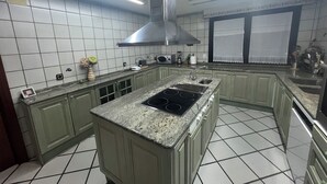 A kitchen with a central island, a range hood, and a tiled backsplash. - Montesión 71 Villa with swimming pool, Puy du Fou (Toledo)