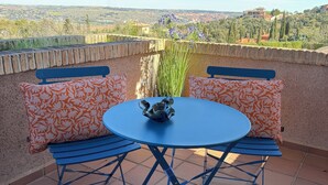 A round table with blue metal legs, two matching blue benches, and orange patterned cushions. - Montesión 71 Villa with swimming pool, Puy du Fou (Toledo)