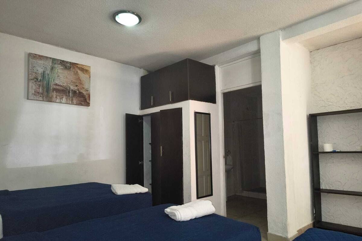 Ein Zimmer mit zwei Betten, einem Schrank, einem Badezimmer und einer Ablagefläche.
