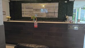 Hotellin vastaanottoalue, jossa on kyltti, jossa lukee ”HOTEL LAS GARDENIAS”, vastaanottotiski, kyltti, jossa lukee ”Tupakointi kielletty”, ja kyltti, jossa lukee ”VASTAANOTTO”.