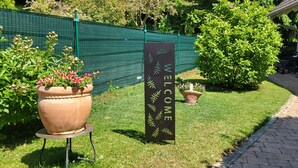 A welcome sign, a potted plant, and a building entrance. - HC 104 big apartement with pool and garden (Haidershofen)
