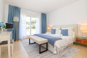 A bedroom with a bed, bedside tables, a desk, and a window with curtains. - Los Monteros Palm Beach, garden & BBQ (Marbella)