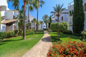 A pathway leading through a well-maintained garden with palm trees and flowering plants. - Los Monteros Palm Beach, garden & BBQ (Marbella)
