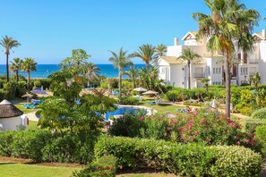 A resort with a swimming pool, palm trees, and a view of the ocean. - Los Monteros Palm Beach, garden & BBQ (Marbella)