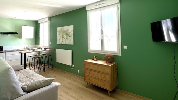 Un espacio habitable moderno con comedor, sofá, cómoda y televisor montado en la pared.