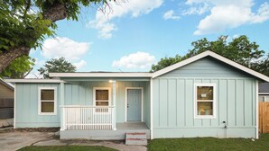 Une maison de plain-pied avec un porche à l’avant, une porte et un petit garage attenant.