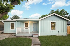 A single-story house with a front porch, a door, and a small attached garage. - Casa de Rio Downtown New Braunfels (New Braunfels)