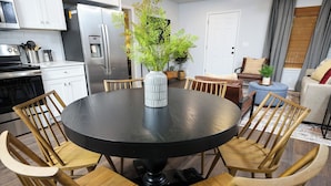 Une cuisine moderne avec un îlot central, des chaises en bois, une table ronde et une plante en pot.