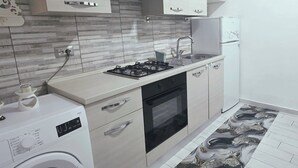 Una cocina compacta con lavadora, estufa a gas y refrigerador.