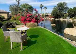 A well-maintained lawn with a small pond, surrounded by various plants and trees.