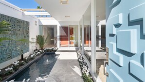 Un edificio moderno con piscina, puertas de vidrio y un diseño de pared geométrico.