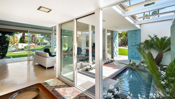 Un interior moderno con una puerta de cristal que da a un patio, una piscina y vistas al exterior.
