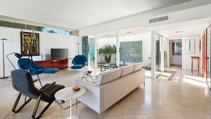 Una sala de estar moderna con sofá, sillones, una mesa de centro y televisor.