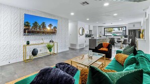 A modern living room with a large TV, a sofa, and a coffee table. - 4BR Resort Home w Pool, Hot Tub & Fire Pit (Palm Springs)