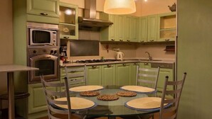 Una cocina moderna con armarios verdes, una mesa de comedor con sillas y una lámpara colgante.