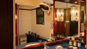 Un baño con un espejo grande, un lavabo y distintos artículos de aseo.