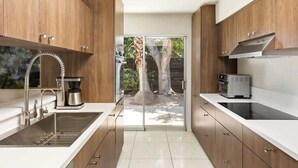 Eine moderne Küche mit Holzausstattung, einem Edelstahl-Spülbecken und einer Glastür zu einem Außenbereich.