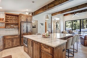 Une cuisine moderne avec des meubles en bois, un îlot en marbre et des luminaires suspendus.