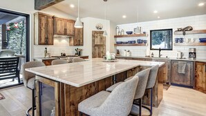 A modern kitchen with a large island, wooden cabinets, and a view of the outdoors. - Modern Mountain Luxury Home w/ Hot Tub, Views, 3BR, Fireplace in Angel Fire. (Angel Fire)