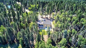 A house surrounded by dense forest, with a clear view of the property and surrounding trees. - Modern Mountain Luxury Home w/ Hot Tub, Views, 3BR, Fireplace in Angel Fire. (Angel Fire)