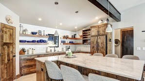 A modern kitchen with a large island, wooden cabinets, and a rustic ceiling. - Modern Mountain Luxury Home w/ Hot Tub, Views, 3BR, Fireplace in Angel Fire. (Angel Fire)