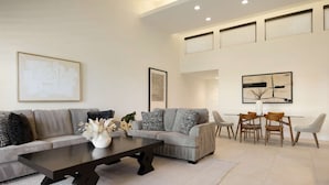 A modern living room with a sofa set, a coffee table, and a dining area with chairs. - Resort Style Condo Getaway in Monterey Country Club (Palm Desert)