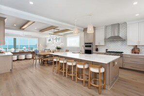 A modern kitchen with a large island, bar stools, and a view to the outside.