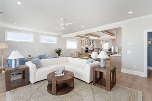 A modern living room with a sectional sofa, two wooden coffee tables, and a ceiling fan.