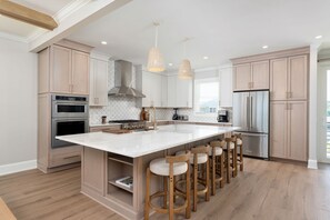 A modern kitchen with a large island, stainless steel appliances, and wooden bar stools.
