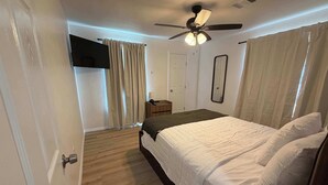 A bedroom with a bed, a ceiling fan, a nightstand, and a door. - 1BR Sleep 4 S Amarillo Corp Stays Tech + Hospital (Amarillo)