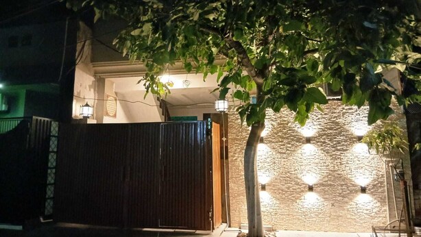 Une entrée fermée par un portail, avec un mur en pierre et un arbre devant.