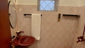 Une salle de bain avec un lavabo rouge, une fenêtre, un porte-serviettes et un bidet.