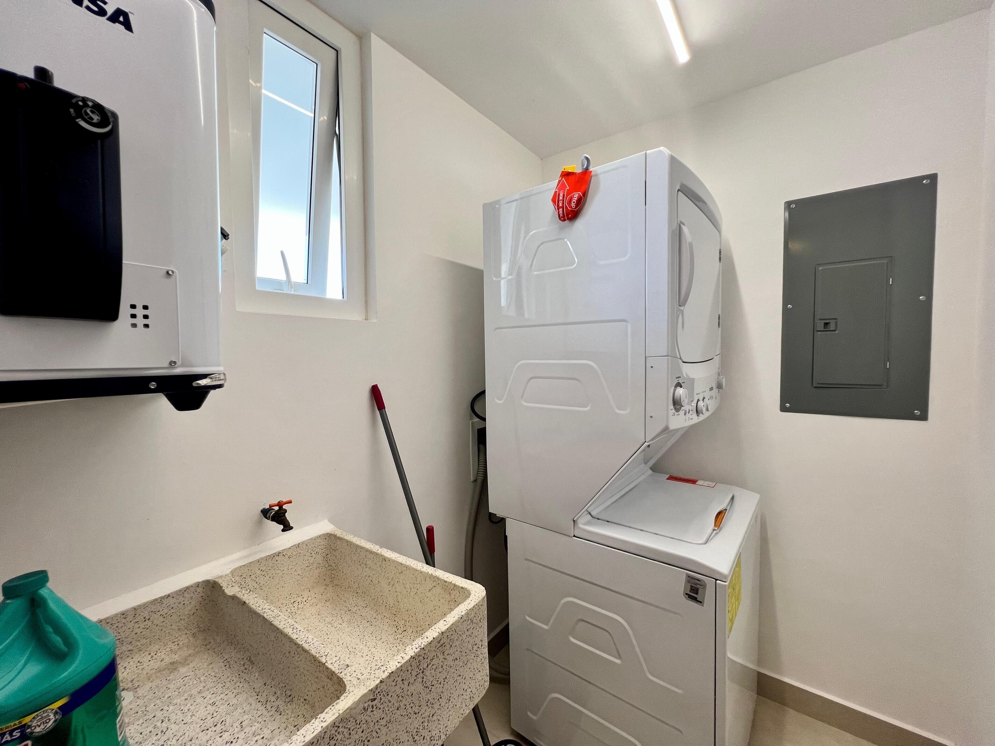 Une buanderie équipée d’un lave-linge, d’un sèche-linge, d’un évier et d’une fenêtre.