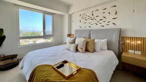 Ein Schlafzimmer mit einem großen Bett, einem Deckenventilator, Blick auf die Stadt und einer Wand mit Dekorationen.