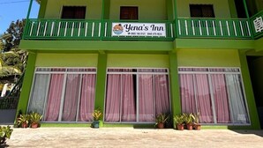 A two-story building with a green facade, balconies, and a sign for 'Yena's Inn' with contact numbers. - Relaxing Escape at Yena’s Inn (Cauayan)