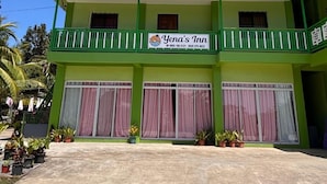 Um edifício de dois andares com fachada verde, varandas e uma placa com o nome 'Yena's Inn'.