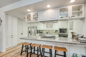 A modern kitchen with white cabinetry, a granite countertop, and bar stools. - Bass Lake Retreat w/community Pool/Yosemite & Lake (Bass Lake)